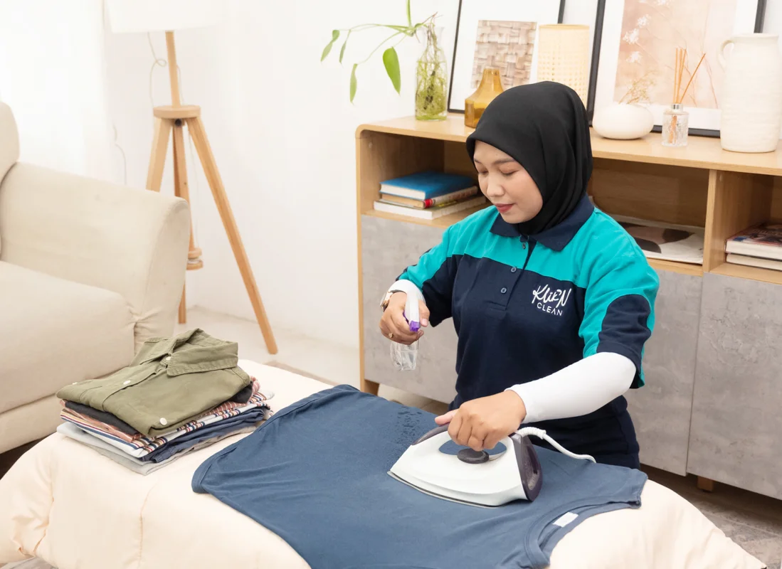 Layanan Setrika KliknClean: helper menyetrika kaos dengan setrika uap