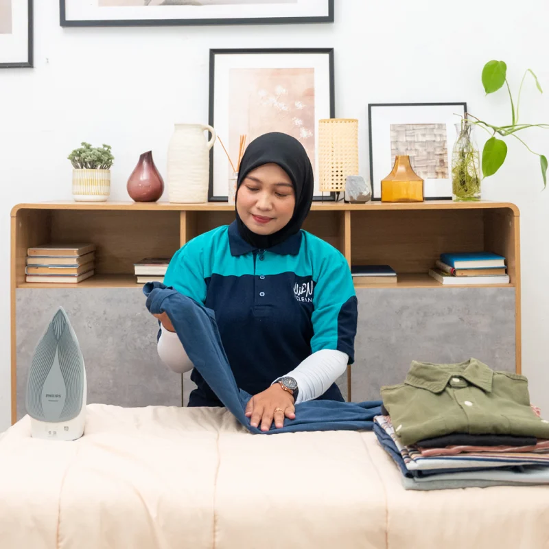 Layanan Setrika KliknClean: helper melipat baju yang sudah disetrika